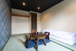 京都Tabist Sparkling Dolphins Inn Kyoto的客房设有桌子、床和桌椅。