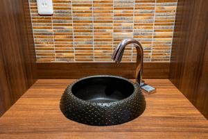 京都Tabist Sparkling Dolphins Inn Kyoto的木柜台上带水龙头的黑色水槽