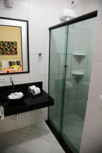 卡拉瓜塔图巴Pousada Sol e Cia Tur的一间带玻璃淋浴和水槽的浴室