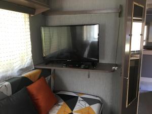 莫罗萨利亚La Caravane LE NID DOUILLET的客厅的架子上配有平面电视