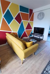 布雷斯特Quatre Moulins - 3 chambres - WIFI - Refait à neuf的客厅设有黄色的沙发和色彩缤纷的墙壁