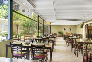 圣保罗Hotel deslumbrante na Vila Olimpia的餐厅设有木桌、椅子和窗户。