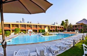 沙迦莎拉罗劳比池度假酒店的酒店游泳池设有椅子和遮阳伞