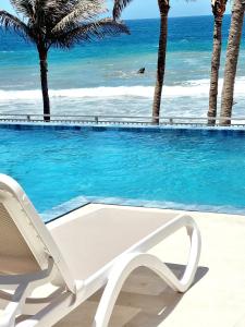 曼克拉Condominio, Las Pocitas de Máncora- Deluxe的白色躺椅,毗邻一个享有海景的游泳池