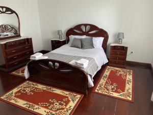蓬塔德尔加达Green Tropical House的一间卧室配有一张带2个床头柜和2个地毯的床