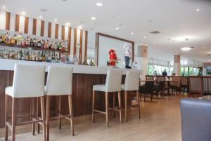 圣保罗Sofisticado Hotel na Vila Olimpia的酒吧餐厅,酒吧,酒吧,有白色的酒吧凳子