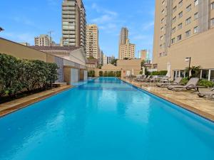 圣保罗Sofisticado Hotel na Vila Olimpia的一座带椅子和建筑的大型蓝色游泳池
