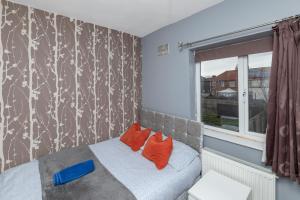 蒂斯河畔斯托克顿Tibbersley House Billingham With Parking的一间卧室配有带橙色枕头的床和窗户。