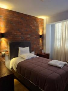 帕卡斯马约Hotel Central Pacasmayo的一间卧室设有一张带砖墙的大床