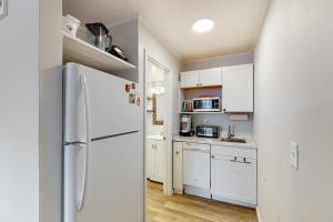大洋城Ocean Waye 226的厨房配有白色橱柜和冰箱。