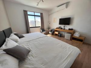 Hu-nei茄萣黄金海岸民宿的卧室配有一张白色大床和电视。