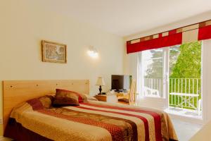 拉拜萨格奈河滨宾馆的一间卧室设有一张床和一个大窗户