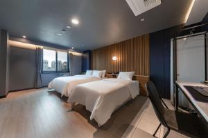 SeosanBrown Dot Hotel Seosan的酒店客房设有两张床和窗户。