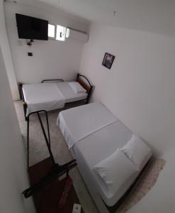 圣玛尔塔Rivera Hostel的小房间设有两张床和电视