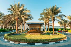 迪拜Le Méridien Dubai Hotel & Conference Centre的一座棕榈树度假村,位于一座建筑前