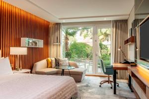 迪拜Le Méridien Dubai Hotel & Conference Centre的酒店客房配有一张床、一张书桌和一台电视。
