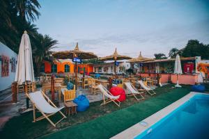 阿斯旺Fenti Nubian Resort的一组椅子和遮阳伞,位于游泳池旁