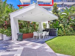 黄金海岸Harbour Quays Apartments的白色天篷下的庭院配有桌椅