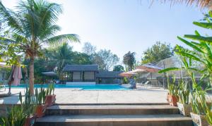 琅勃拉邦Luang Prabang chanon hotel的一个带游泳池和棕榈树的度假村