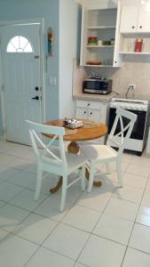 拿骚Lynn's Cozy Cottage的厨房配有木桌和两把白色椅子