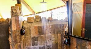 奥马鲁鲁Ondudu Safari Lodge的石墙客房的淋浴