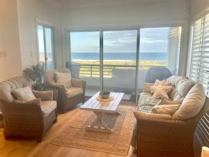 StocktonBeach House on Stockton Beach, Newcastle的客厅配有沙发、椅子和桌子