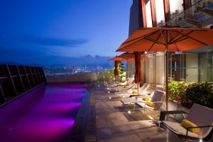 香港Nina Hotel Kowloon East的一座带椅子和遮阳伞的建筑屋顶游泳池