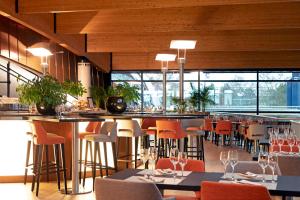 卢森堡d'Coque Hotel的餐厅设有酒吧,配有橙色椅子和桌子