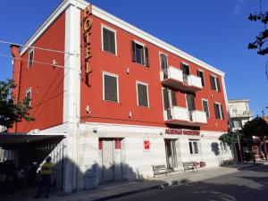 圣安蒂奥科意大利餐厅摩登酒店的一座红白的建筑,前面有一个人站在