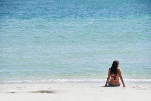 塞拉莱Juweira Boutique Hotel Adult only的坐在海滩上看着水面的女人