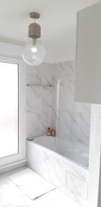 巴纽La Terrasse - big apartment & terrace 80m2 - metro 17 min from Paris的白色的浴室设有浴缸和窗户。