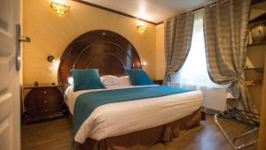 欧村Ault - Villa Aultia Hotel - baie de somme的一间卧室配有一张大床和木制床头板