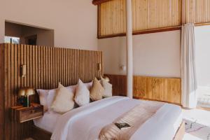 达赫拉Caravan by Habitas Dakhla的卧室配有一张白色大床和木制床头板