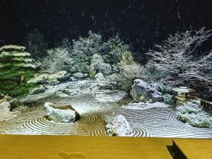 箱根Onsen & Garden -Asante Inn-的雪中花园,有岩石和树木