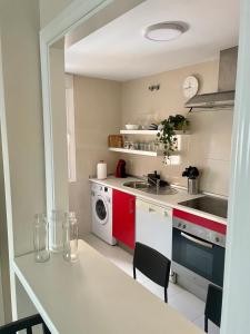 博尔穆霍斯Apartamento Liru Bormujos, a 5 minutos de Sevilla的厨房配有红色和白色的家电和桌子