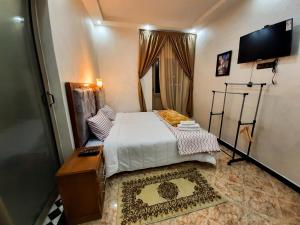 达赫拉DARKOM的一间小卧室,配有一张床和一台平面电视