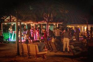 CanouanSoho Beach House Canouan的一群人坐在晚上的聚会上