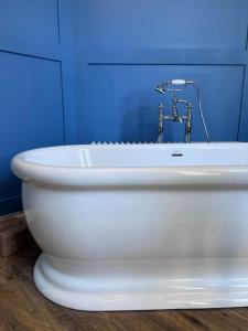 莫法特Moffat House的浴室设有白色浴缸,拥有蓝色的墙壁