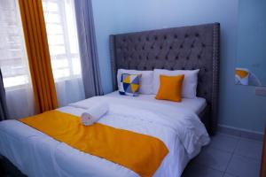 Langata RongaiSpringStone executive suite Rm 18的一间卧室配有一张带橙色枕头的大床