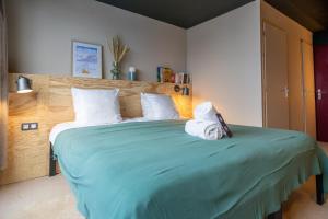 里蒙纽耶ho36 Les Menuires的一间卧室配有一张带两条毛巾的大型绿床