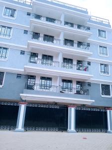 Langata RongaiSpringStone executive apartment Rm 4的带阳台和围栏的大型白色建筑