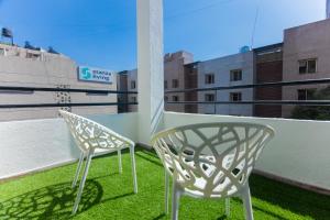 浦那La vaccanza Suite -403的两把白色椅子坐在带绿草的阳台