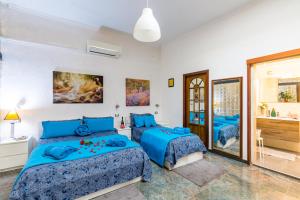 那不勒斯Museo Filangieri Apartment-Suite的一间带2张蓝色床的卧室和一间浴室
