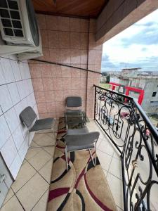 杜阿拉AU COEUR DE BONAMOUSSADI-WIFI-PARKING-GARDIENS-24H的阳台配有两把椅子、一张桌子和一台微波炉。