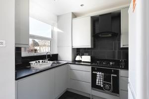 Enfield LockSkyvillion - London Enfield 4 Bedroom Lush House Free Parking Garden的厨房配有白色橱柜和黑色台面
