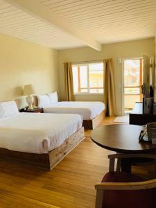 洋滨市海洋海岸旅馆&套房酒店的酒店客房设有两张床和一张桌子。