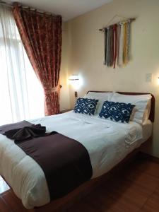 万卡约CasaHotel Centro - Huancayo的一间卧室配有一张带蓝色枕头的大床和窗户。