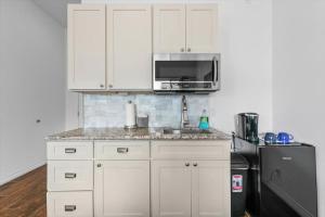 怀卢库Unit 15 Maui Ohana Modern Studio的厨房配有白色橱柜、微波炉和冰箱。