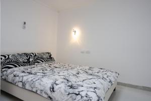 迈季代勒舍姆斯Dove Suites的白色卧室配有一张带黑白色棉被的床