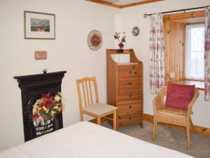 OllachThe Cottage的一间卧室配有一张床、一个壁炉和一把椅子